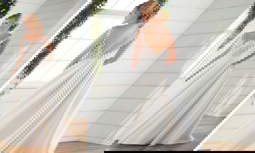 Detailreiches Brautkleid mit Spitze und weit ausgestelltem Rock. Das Kleid hat einen tiefen Rückenausschnitt, der in einer langen Knopfleiste endet.