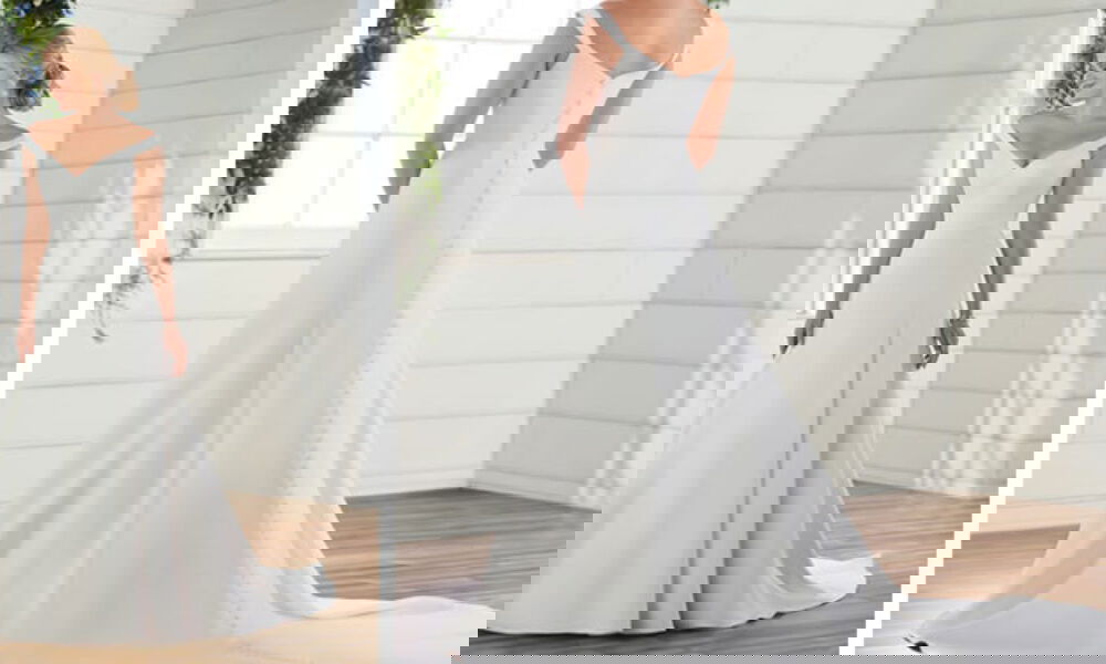 Schlichtes Brautkleid mit schulterfreiem Ausschnitt und eleganter Schleppe, perfekt für einen klassischen Hochzeitslook. Die Rückansicht zeigt eine durchgehende Knopfleiste.