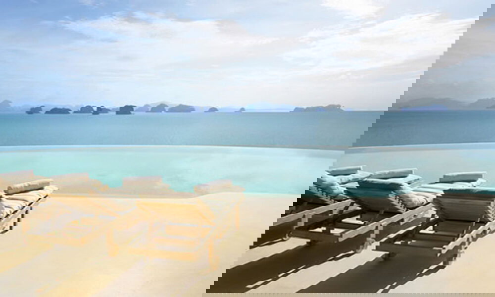 Infinity Pool mit Meerblick und gemütlichen Liegen im Vordergrund, perfekt für eine entspannte Auszeit mit Blick auf thailändische Inseln.