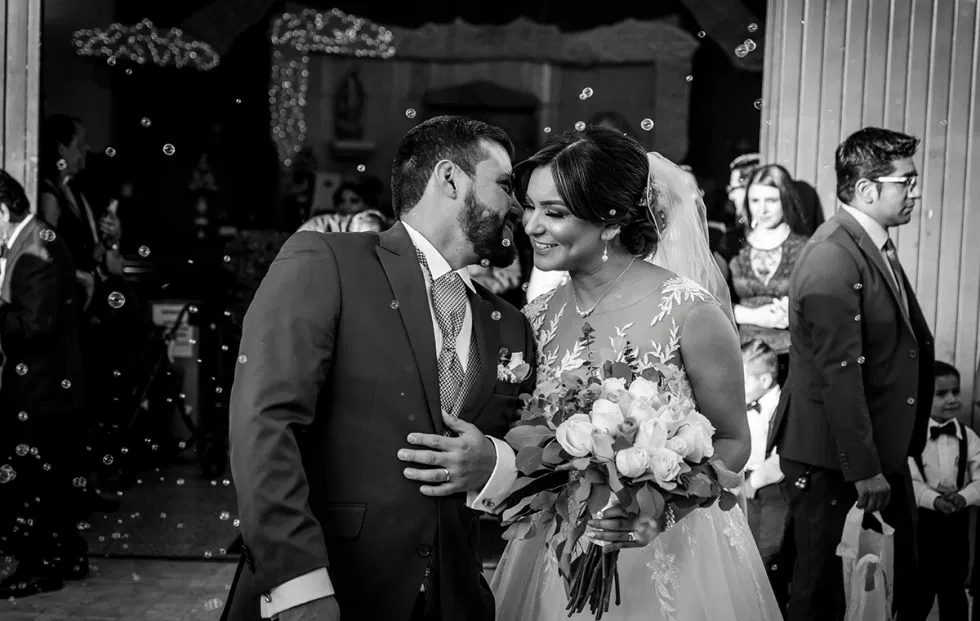 Brautpaar beim Auszug aus der Trauung, umgeben von schwebenden Seifenblasen – romantische Alternative zum Reiswerfen bei Hochzeiten.