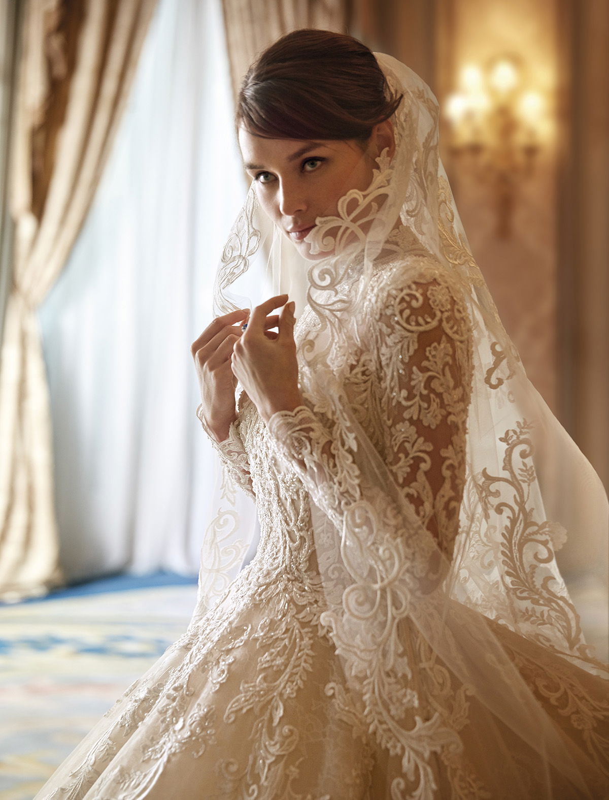 Romantischer Braut-Look mit Spitzenkleid und Schleier, der das Gesicht umspielt, ideal für eine elegante und stilvolle Hochzeit.