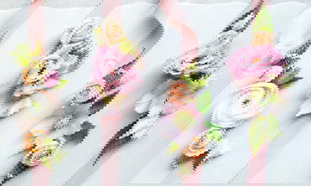 Schmuckbänder aus Blumen in sanften Pastellfarben und rosa Bändern, sorgfältig gestaltet für eine romantische Hochzeit.