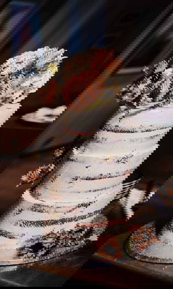 Eine dreischichtige Naked Cake Torte mit dezenter Blumendekoration, ideal für eine romantische Hochzeitsfeier.