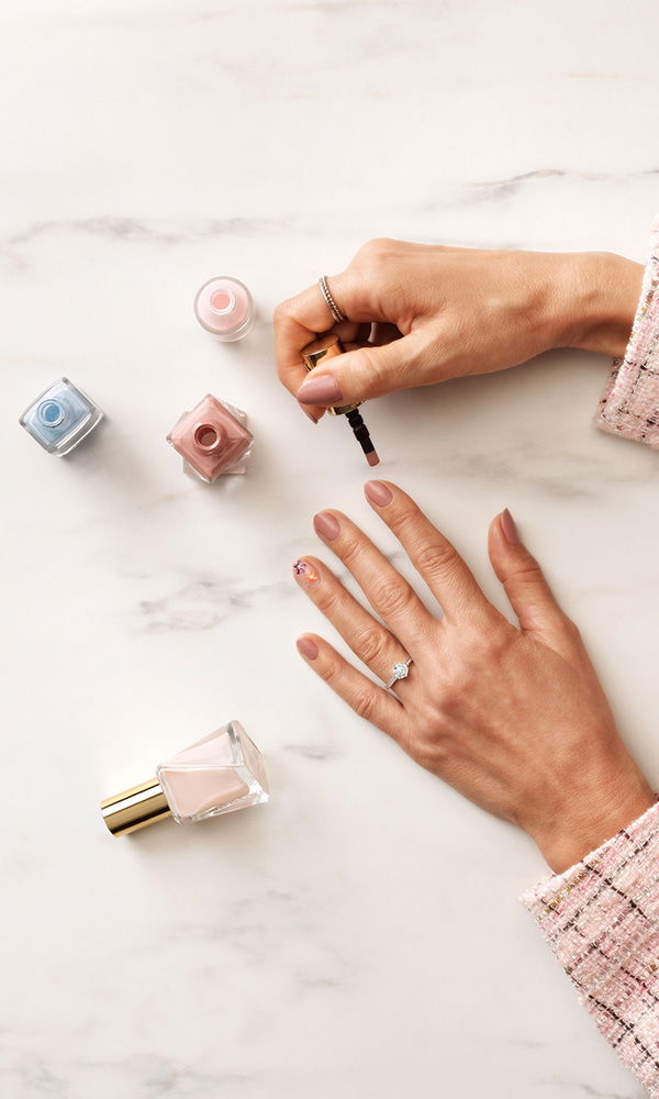 Stilvolle DIY-Nagelpflege mit Verlobungsring auf hellem Marmorhintergrund.