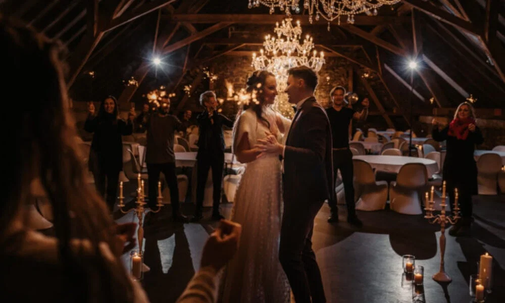 Der Hochzeitstanz des Brautpaares in einer stimmungsvoll beleuchteten Scheune, umgeben von Gästen, die funkelnde Wunderkerzen in den Händen halten.