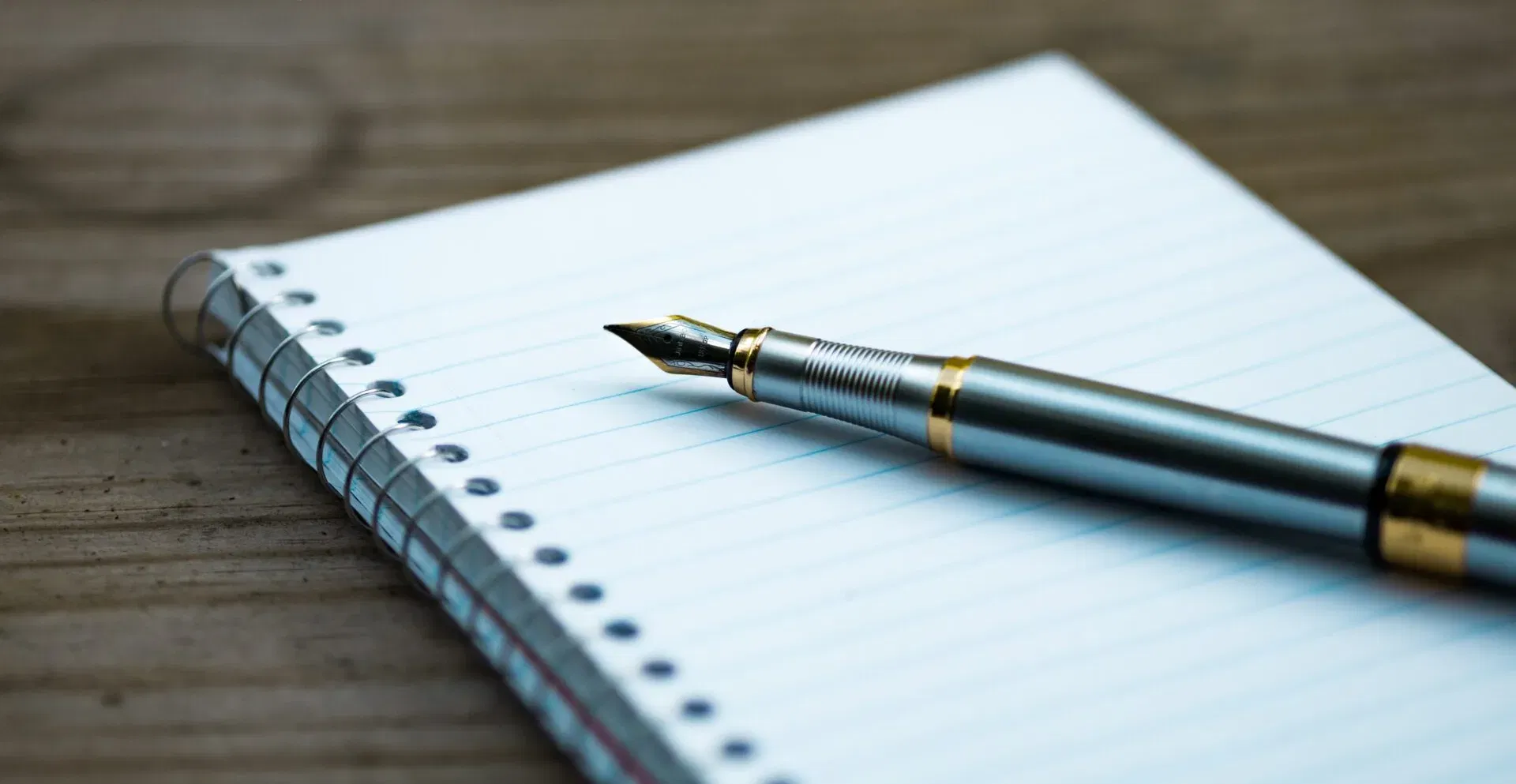 Detailaufnahme eines hochwertigen Füllfederhalters auf einem linierten Schreibblock – Symbol für Kreativität und persönliche Worte.