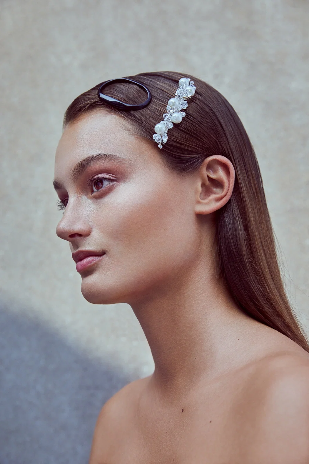 Profilansicht einer Frau, die eine edle Haarspange aus Perlen trägt. Ihr schlichtes, elegantes Make-up verleiht ihr ein harmonisches Aussehen.