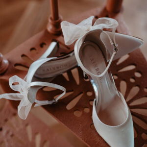 Weiße Brautschuhe mit einer Tüllschleife an der Ferse, stehen auf einer Wendeltreppe