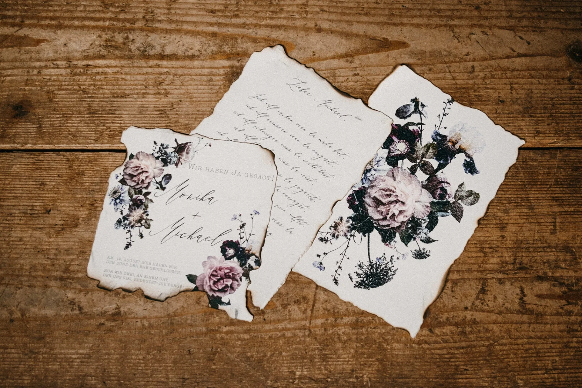 Hochzeitseinladungen im Landhausstil, verziert mit Blumendekor und Handlettering auf Pergamentpapier mit antik angehauchten, verbrannten Rändern.
