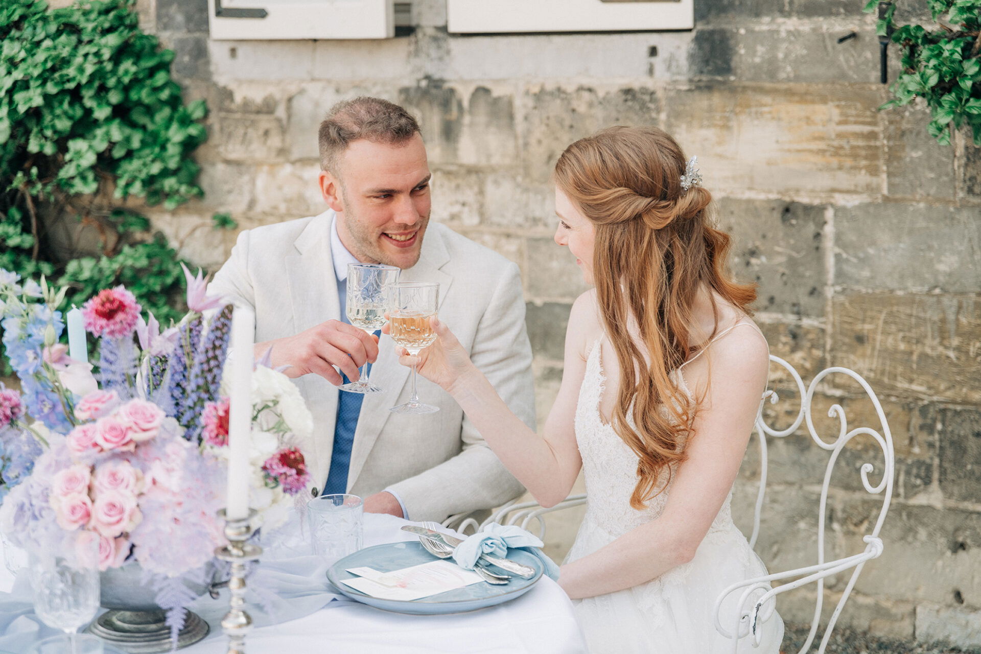 Das frisch verheiratete Paar hebt die Gläser zum Anstoßen, während sie sich bei ihrer Feier draußen innig ansehen.
