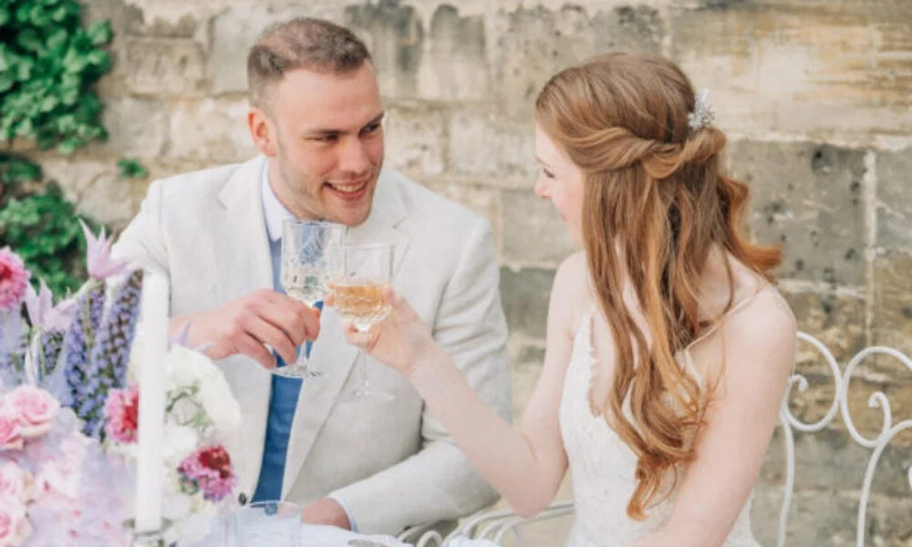 Fröhliches Brautpaar feiert mit einem romantischen Glas Sekt im Freien, während sie den besonderen Tag miteinander teilen.