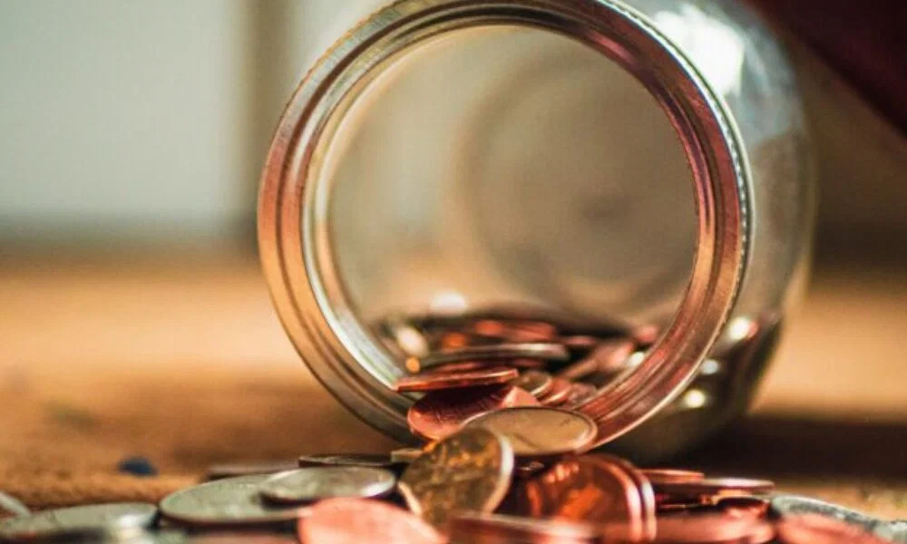 Eine Ansammlung von Münzen, die aus einem Glas herausfallen, als Symbol für finanzielle Planung und Budgetmanagement.