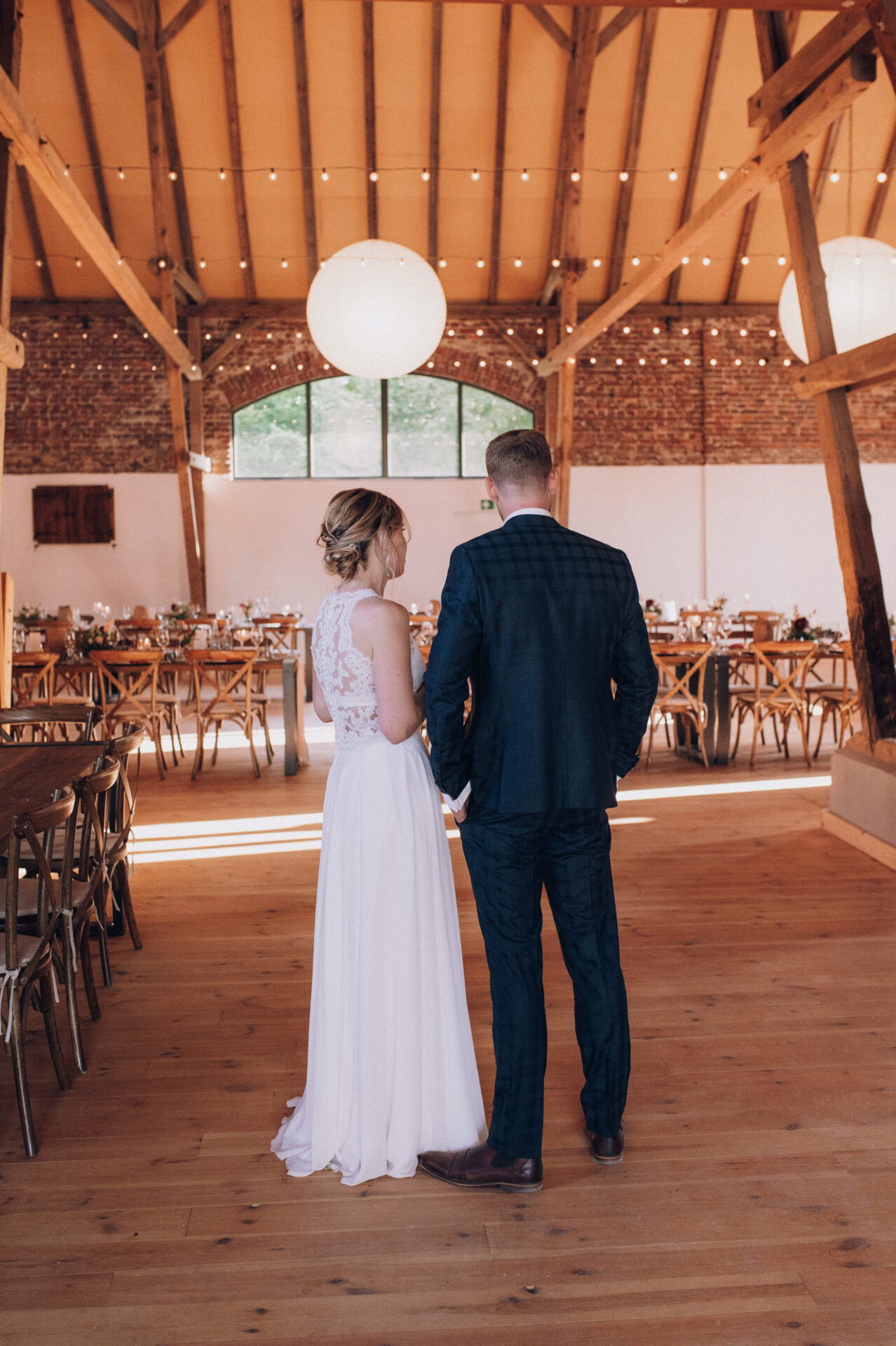Das Brautpaar blickt in einen romantisch dekorierten Saal mit großen runden Lampen und einer festlichen Atmosphäre.