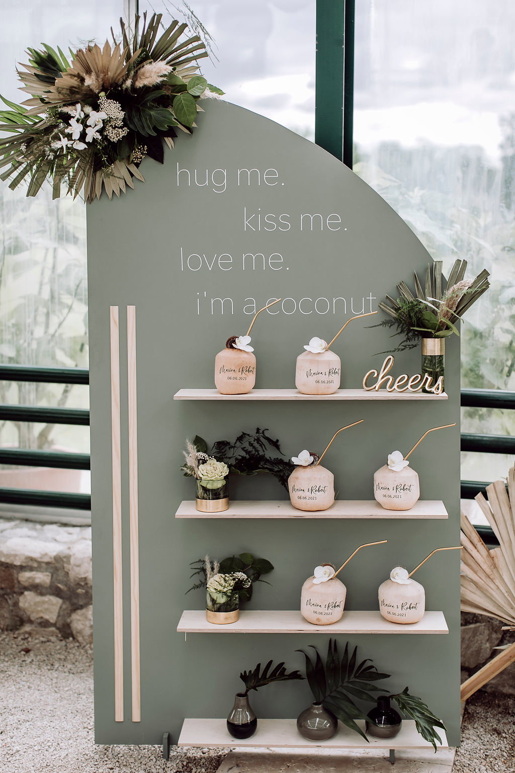 Tropische Hochzeitsbar mit beschrifteten Kokosnüssen und grünen Pflanzen, perfekt für eine entspannte Bali-inspirierte Feier.