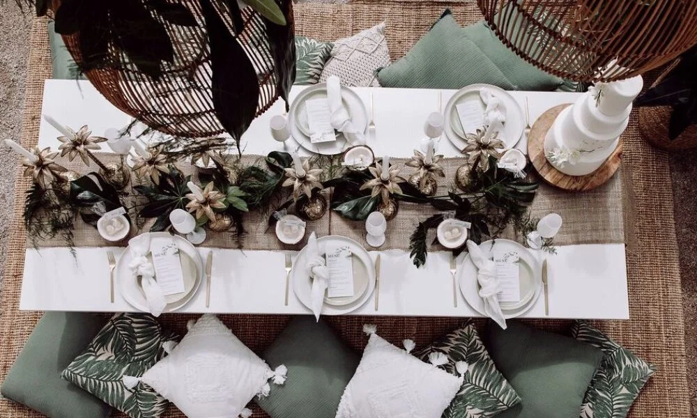 Stilvolle Tischdekoration für eine tropische Bali-Hochzeit mit natürlichen Textilien, grüner Boho-Deko und weißen Kerzen.