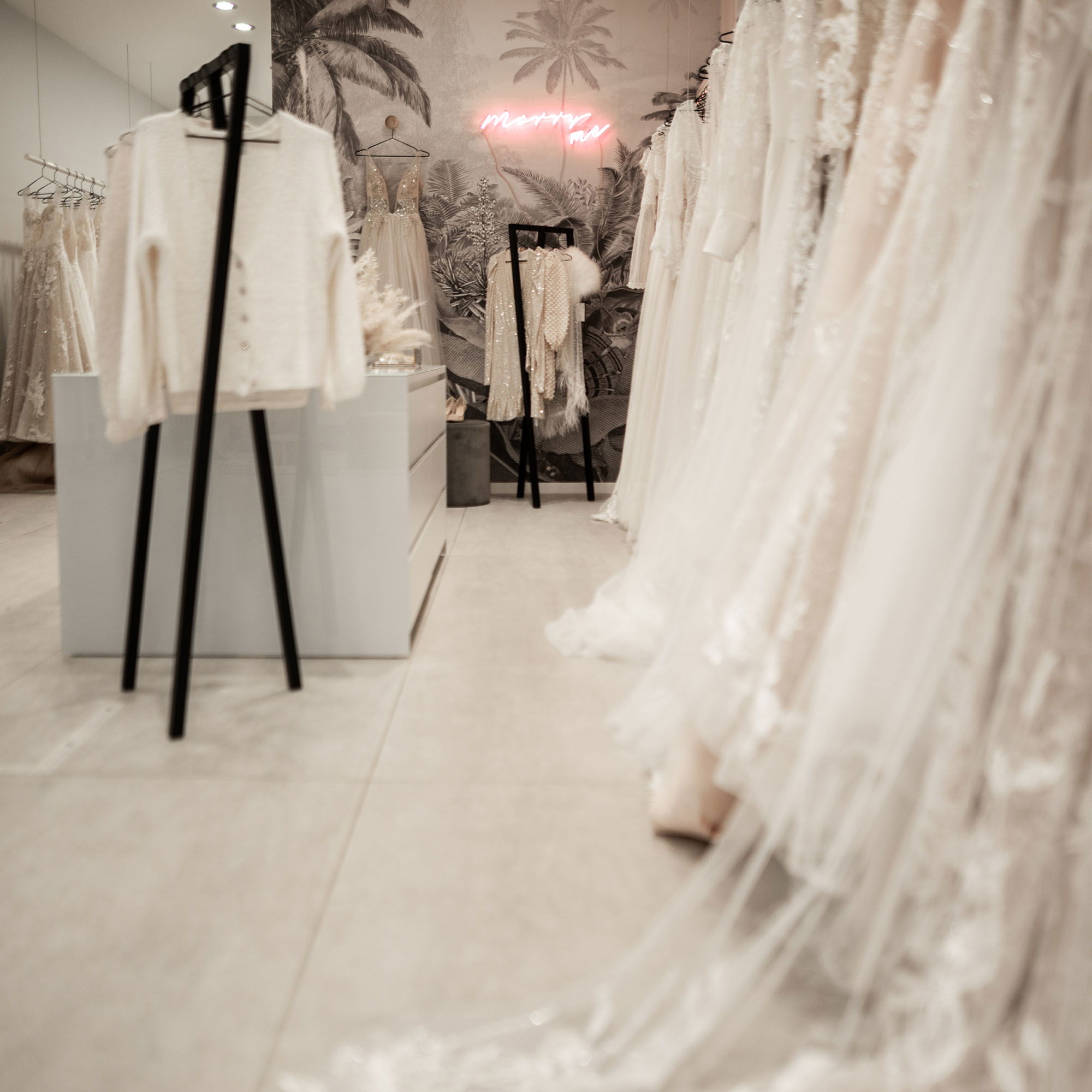 Eine Kollektion von Brautkleidern, ausgestellt in einem modernen Brautmodenladen, mit dezenter Dekoration und klaren Linien.
