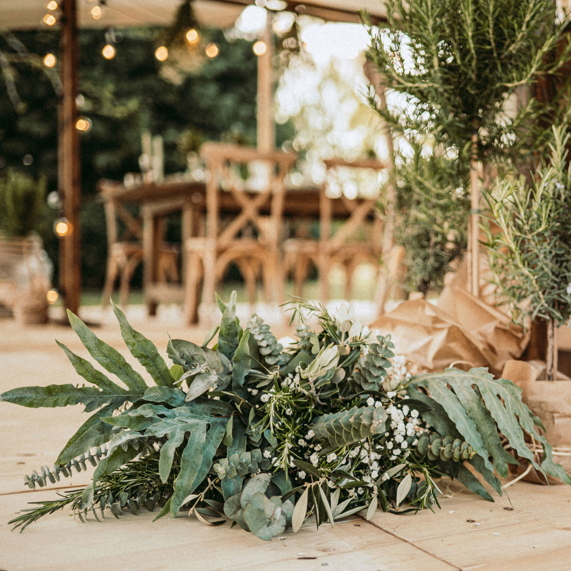 Hochzeitsdekoration mit frischen Eukalyptus- und Olivenzweigen, die eine warme, rustikale Atmosphäre schaffen.