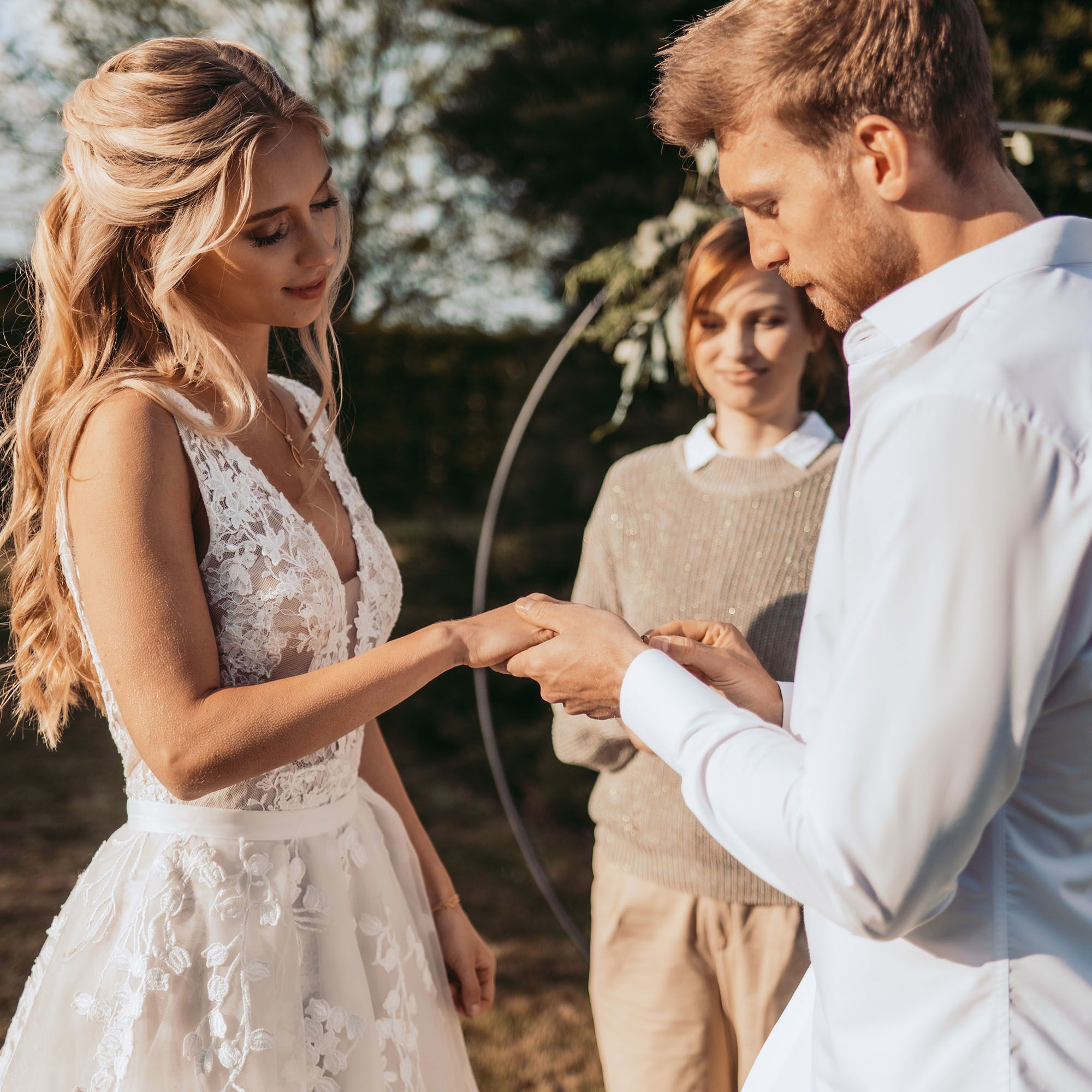 Zeremonie im Freien: Das Brautpaar wechselt die Ringe in einem intimen, sonnigen Gartenambiente.