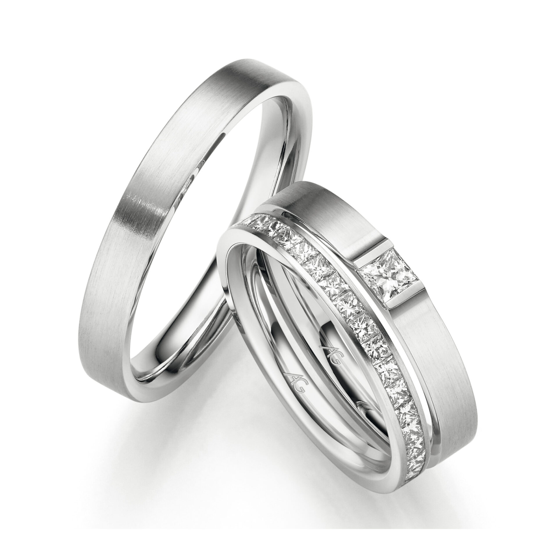 Ein Set aus Platinringen: Der Verlobungsring ist mit funkelnden Princess-Cut-Diamanten verziert, während der Ehering schlicht und mit einer matten Oberfläche gestaltet ist.