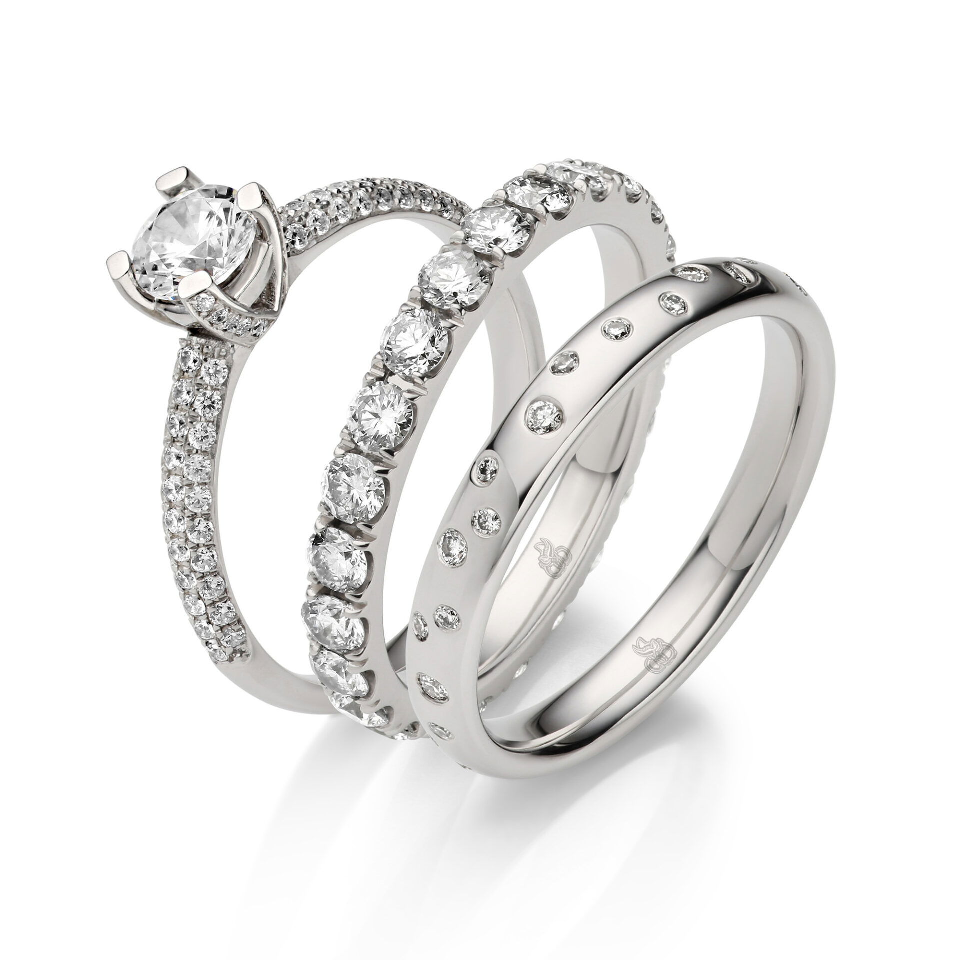 Ein luxuriöses Set aus drei Diamantringen, bestehend aus einem Verlobungsring mit Solitär-Diamant und zwei Eheringen, die mit Diamanten in unterschiedlichen Größen um den gesamten Ring besetzt sind.