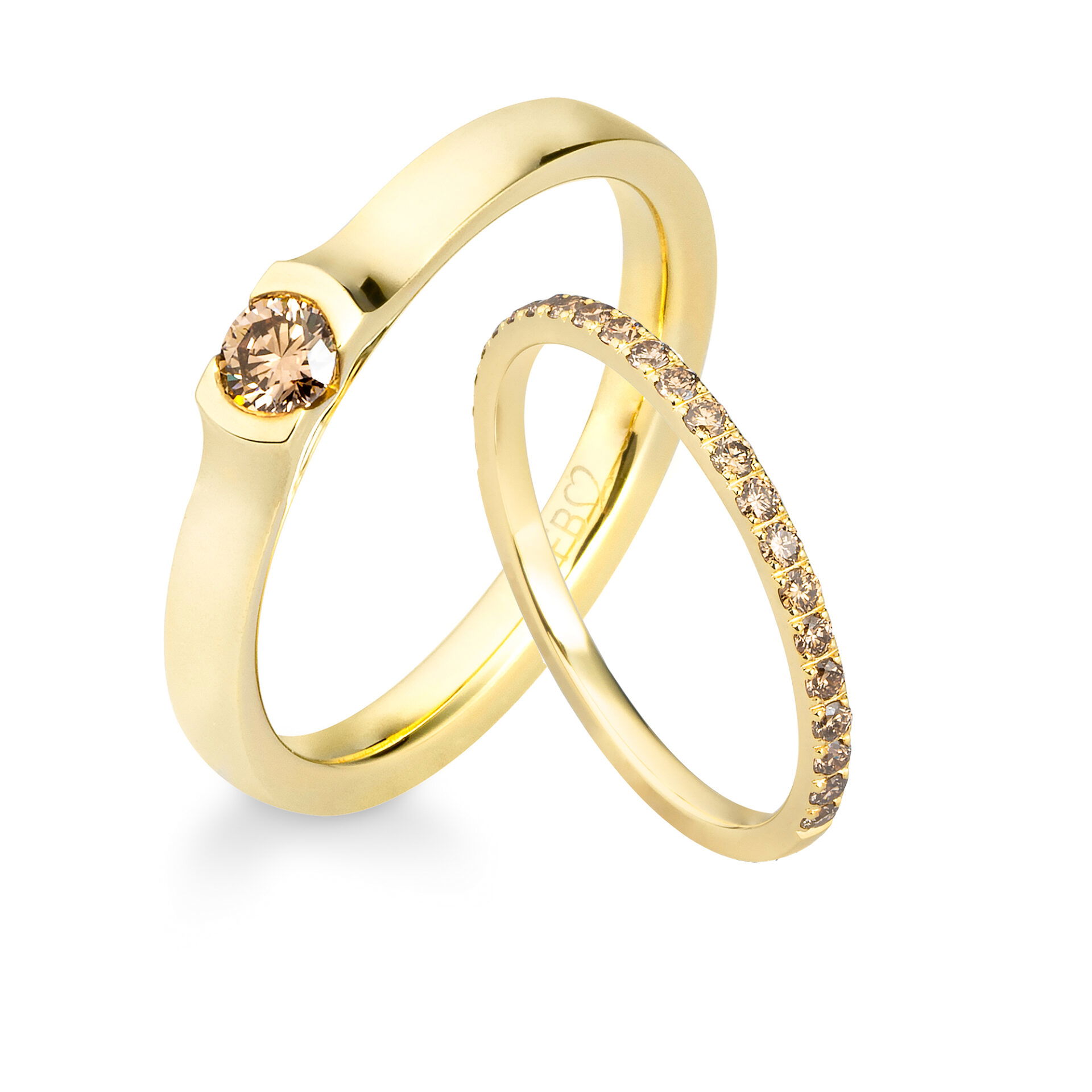 Zwei filigrane Ringe aus Gold. Der größere Ring hat einen champagnerfarbenen Diamanten als Hauptstein, während der schmale Ring mit einer Reihe kleiner Diamanten besetzt ist.