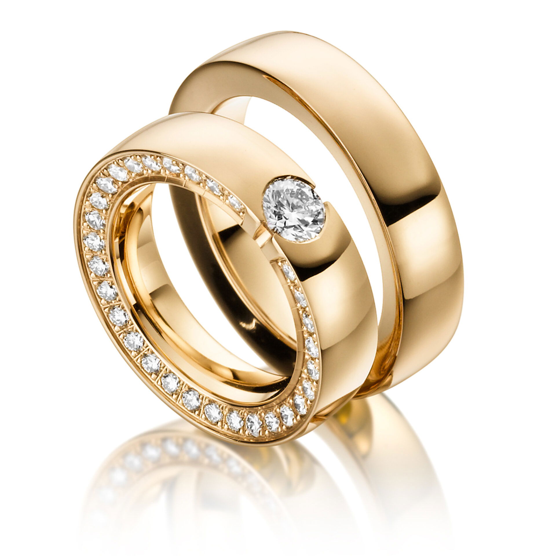 Eine Gruppe von drei massiven goldenen Ringen. Einer der Ringe hat einen zentralen Diamanten, die anderen zwei sind mit Diamanten besetzt und ergänzen das Set auf edle Weise.