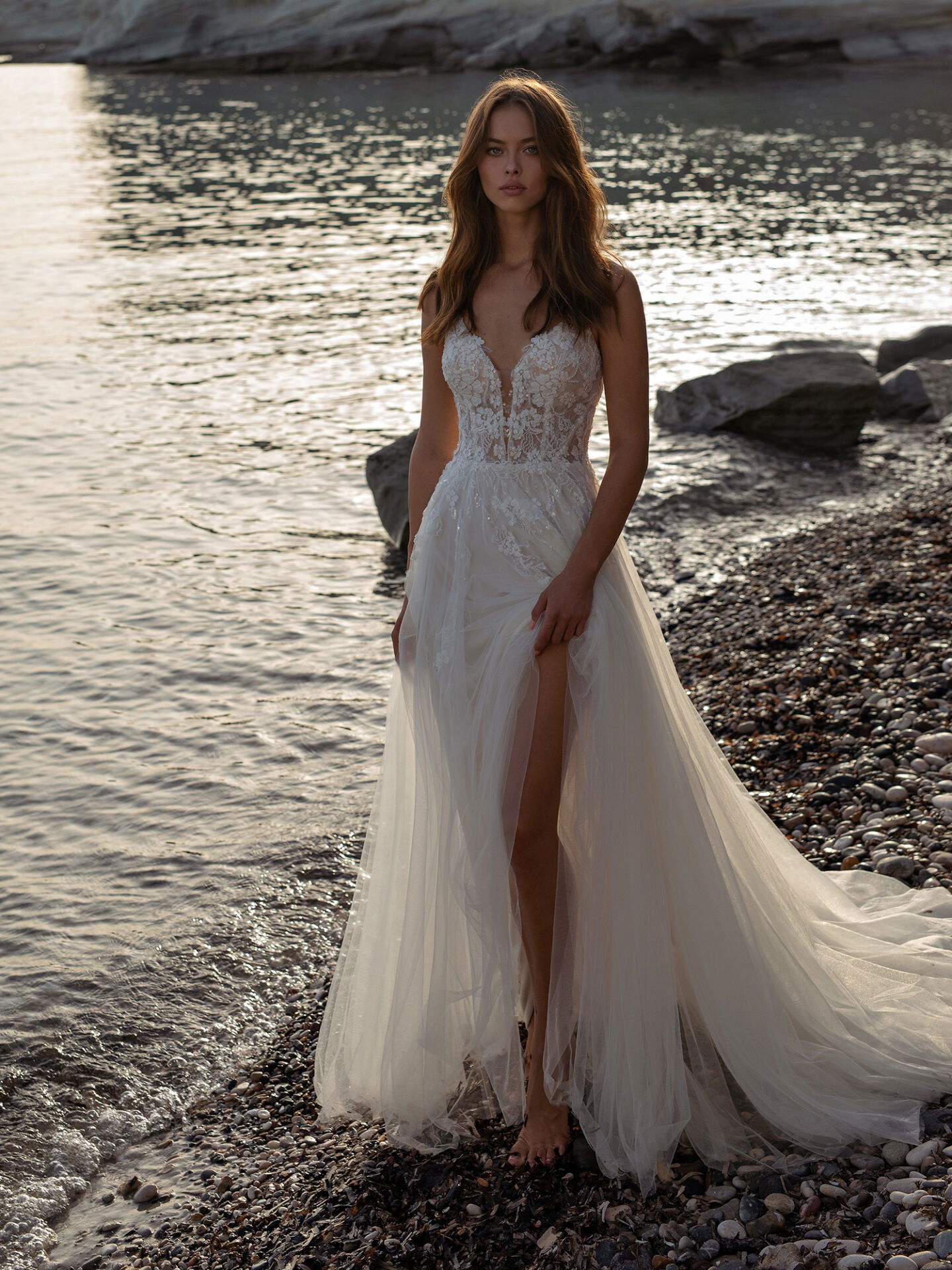 Braut im Hochzeitskleid mit Beinschlitz am Strand