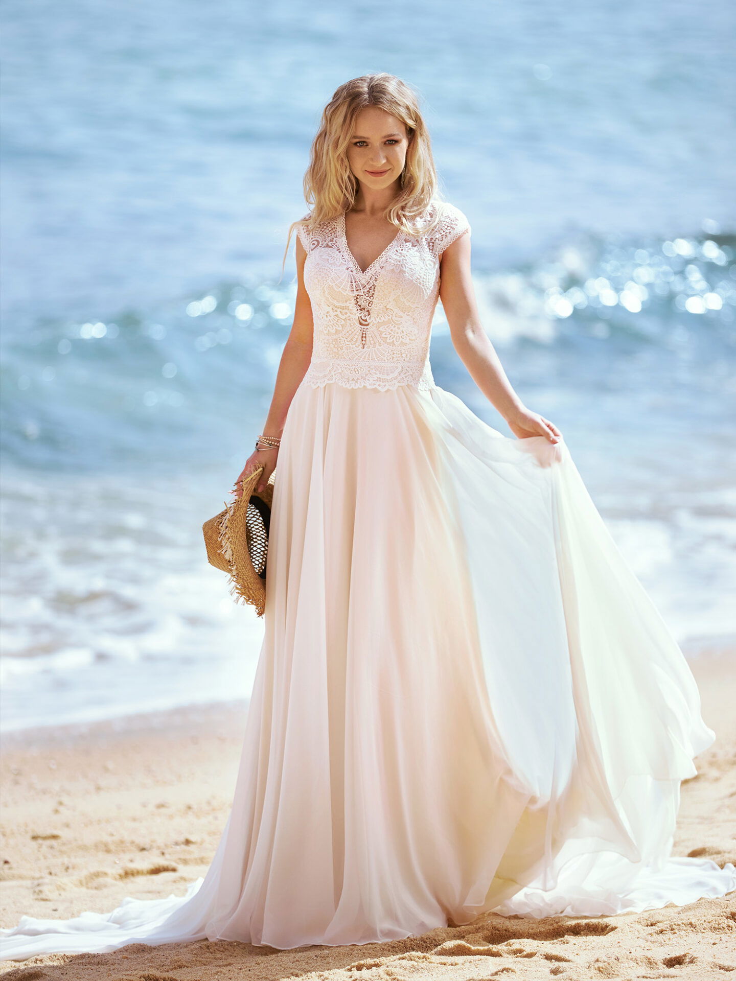 Braut im Hochzeitskleid ihre Schleppe haltend am Strand