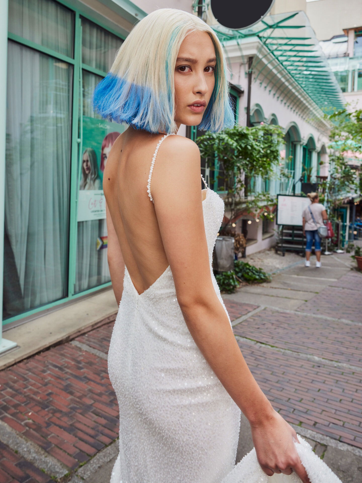Braut im Hochzeitskleid mit blau gefärbten Haaren posiert auf der Straße