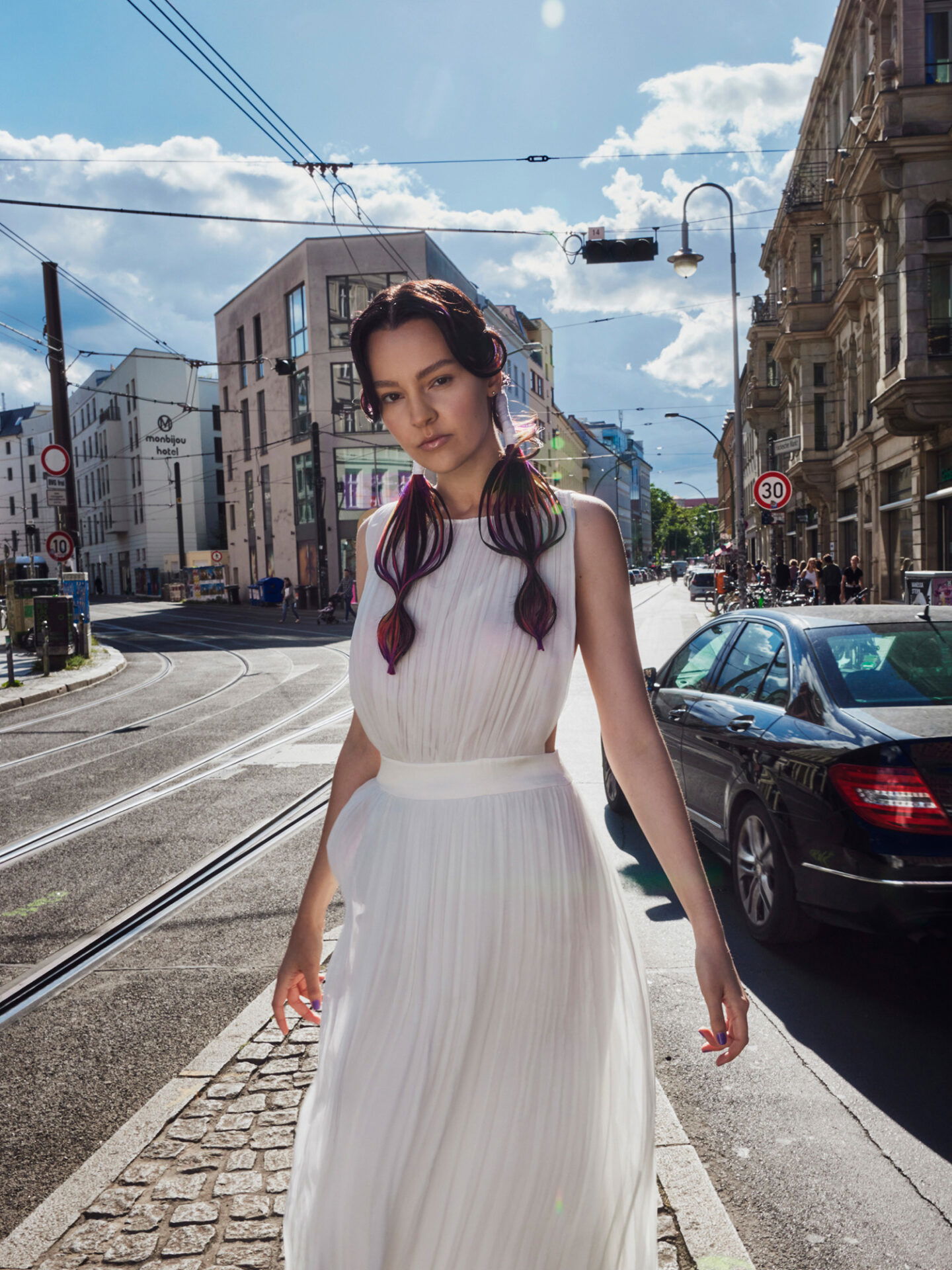 Braut im Hochzeitskleid mit bunt gefärbten Haaren posiert auf der Straße