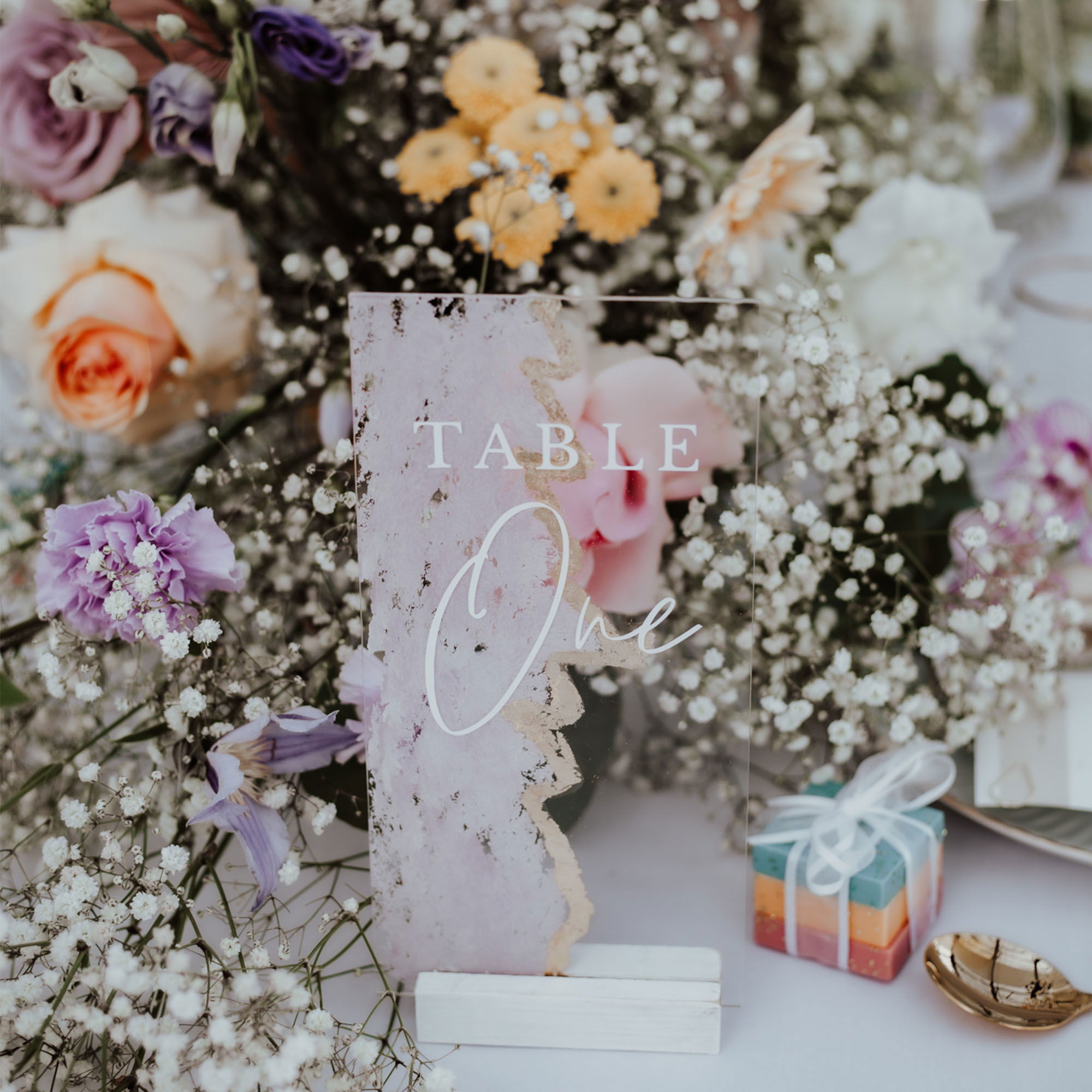 Blumige Hochzeitstafel mit romantischer Dekoration in zarten Farbtönen, mit handgeschriebener Tischnummer und leuchtenden Kerzen als Highlight.