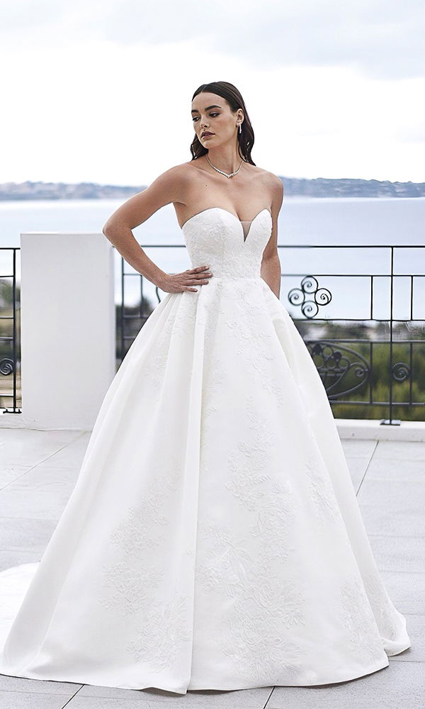 Elegantes Hochzeitskleid mit floralen Verzierungen und zarten Trägern, perfekt für eine klassische Braut.