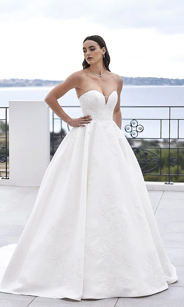 Elegantes Hochzeitskleid mit floralen Verzierungen und zarten Trägern, perfekt für eine klassische Braut.