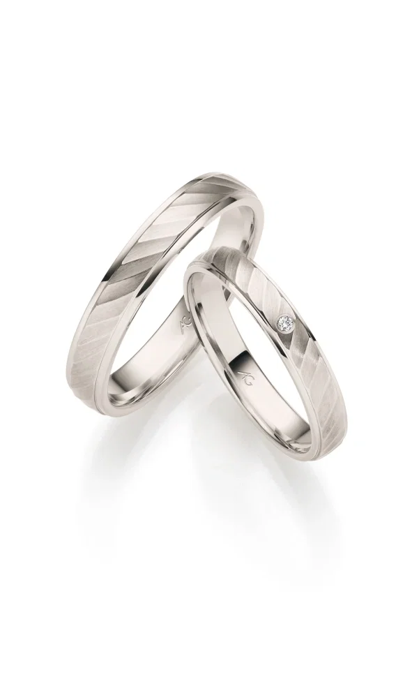 Moderne Eheringe aus hellem Gold mit mattierter Oberfläche und feiner Linienführung sowie kleinem Brillant