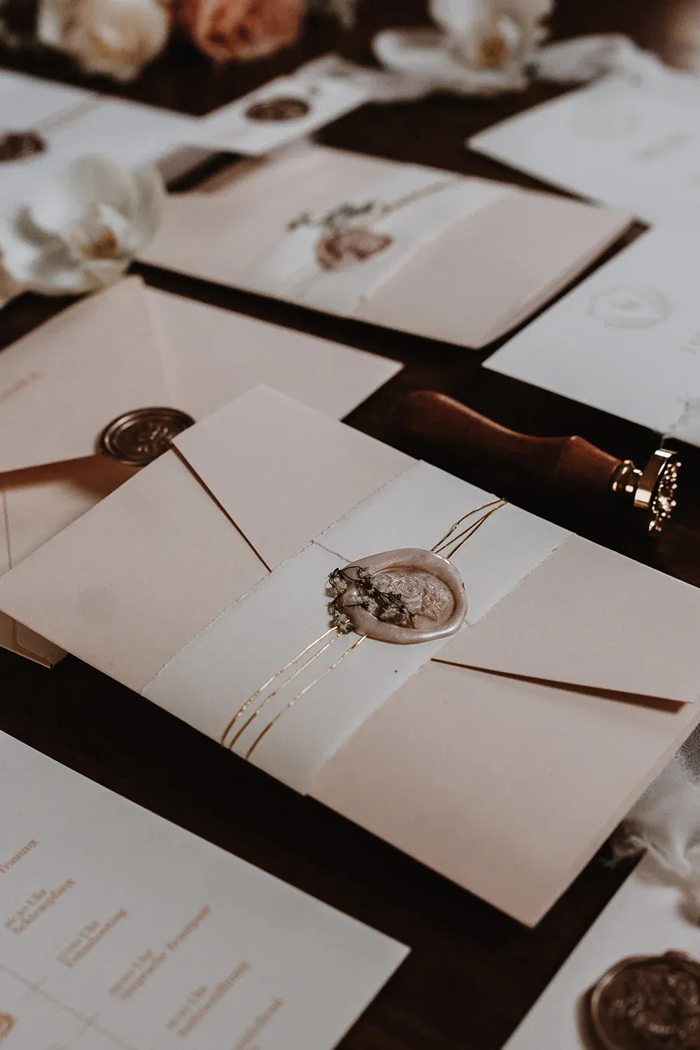 Umschläge mit Wachssiegeln und goldenen Fäden für eine Hochzeitseinladung. Ein Arrangement mit feinen Details und eleganter Hochzeitsdekoration.