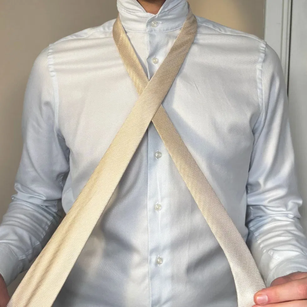 Die breite Seite der Krawatte wird über die schmale Seite gelegt, sodass sich ein X auf der Brust bildet.