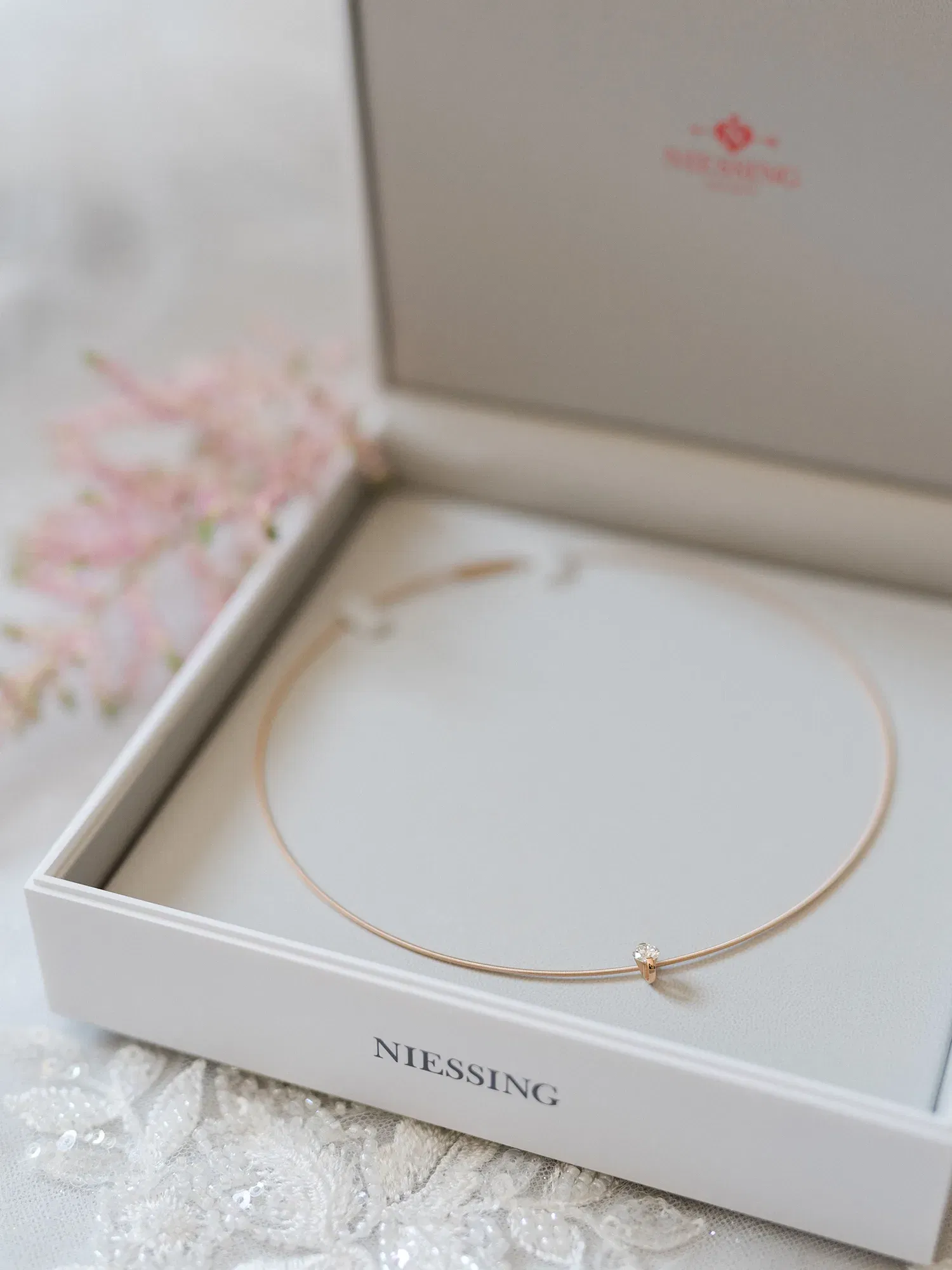 Eine feine Goldkette mit einem dezenten Diamanten wird in einer schlichten, geöffneten Schachtel präsentiert. Die Kette strahlt durch ihre Schlichtheit Eleganz aus.