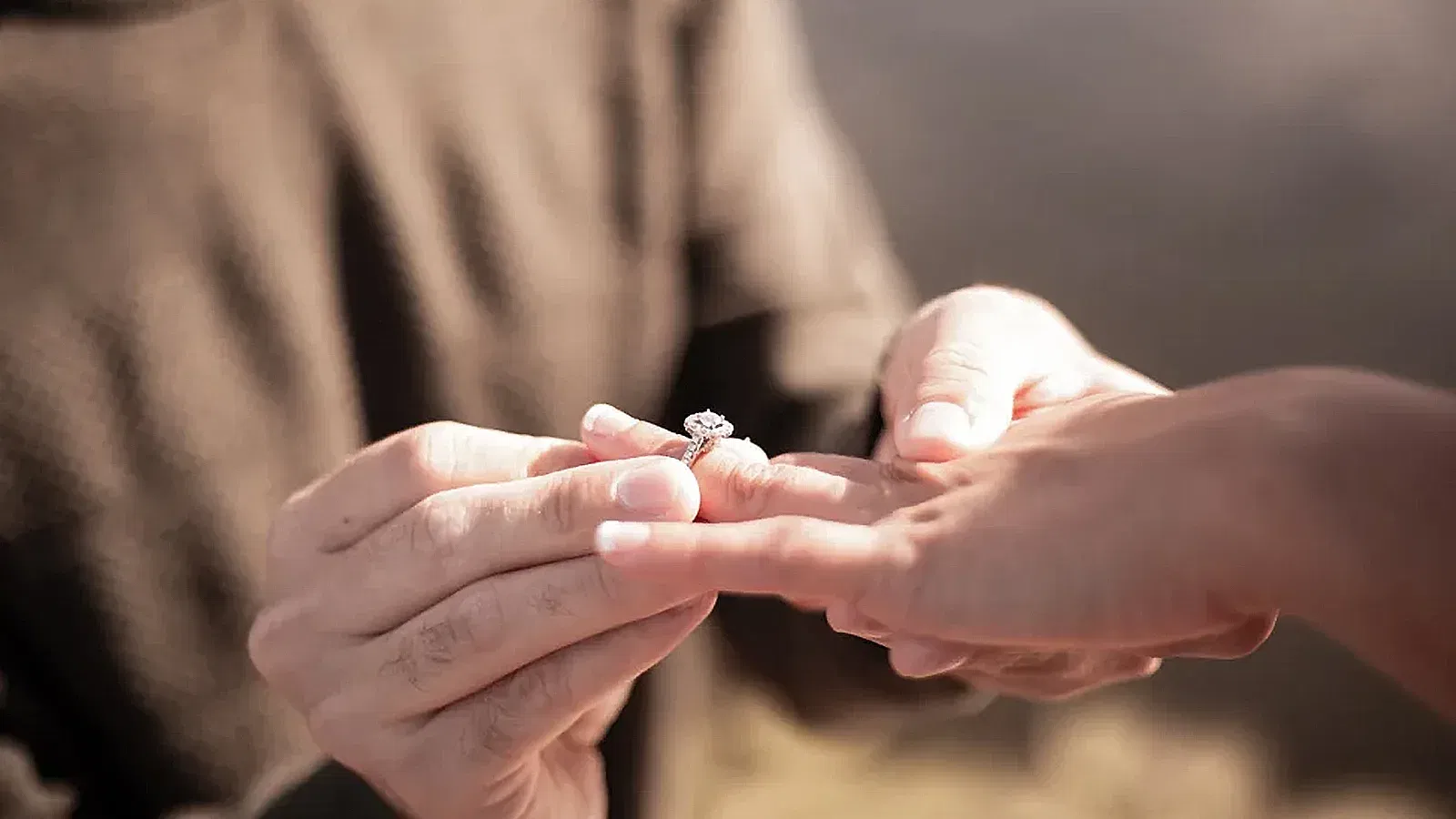 Verlobungsring-Zeremonie: Eine Hand steckt einem Partner einen Ring an den Finger, Symbol der Liebe und des Engagements.