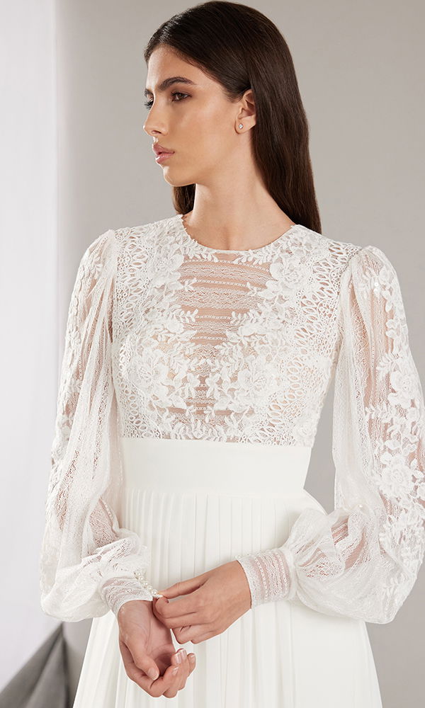 Braut in einem romantischen Spitzenoberteil mit langärmeligen Details und feiner Handarbeit.