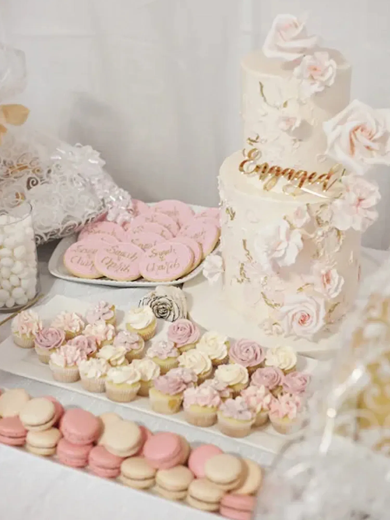 Verlobungsbuffet mit dekorativer Torte, Cupcakes und Macarons, alles in zarten Pastellfarben arrangiert.