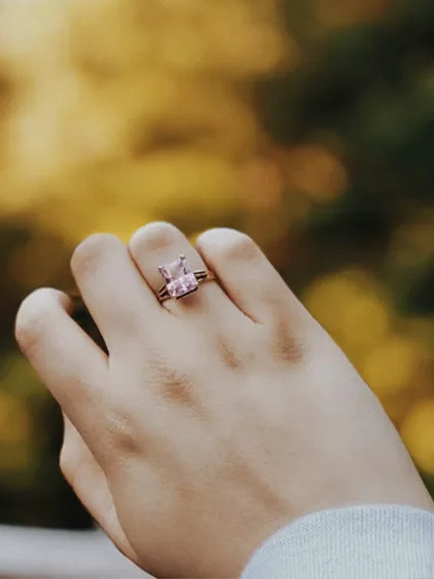 Eine Hand mit einem farbenfrohen Verlobungsring, der im warmen Licht eines Herbsttages erstrahlt.
