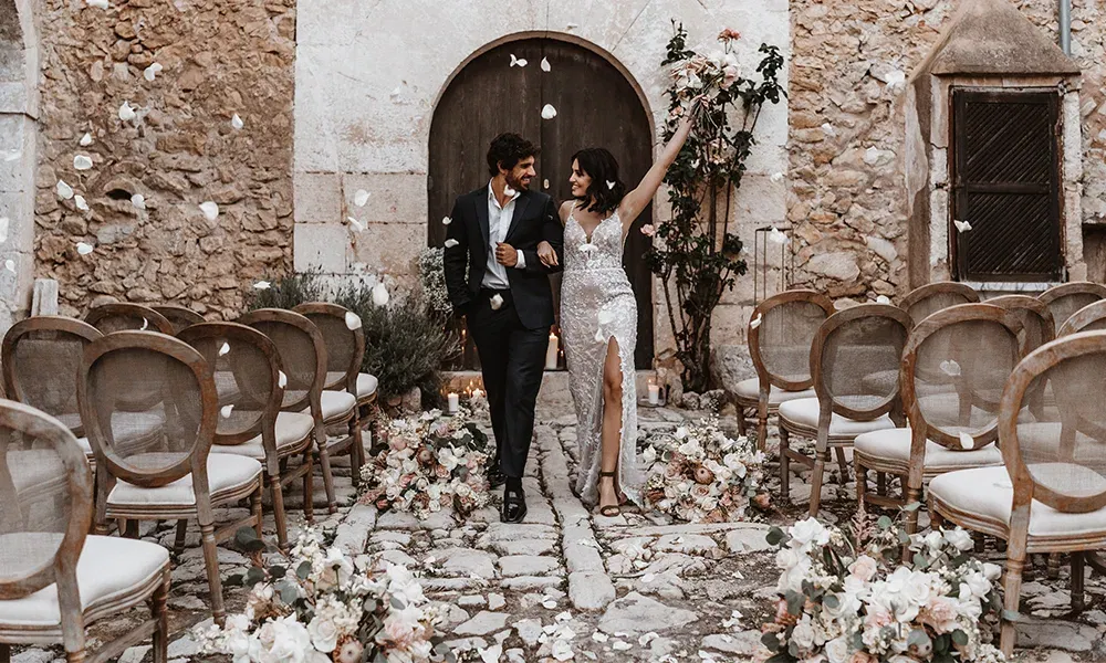 Das Brautpaar feiert seinen Hochzeitstag, während es durch einen malerischen, mit Blumen gesäumten Gang spaziert, Arm in Arm.