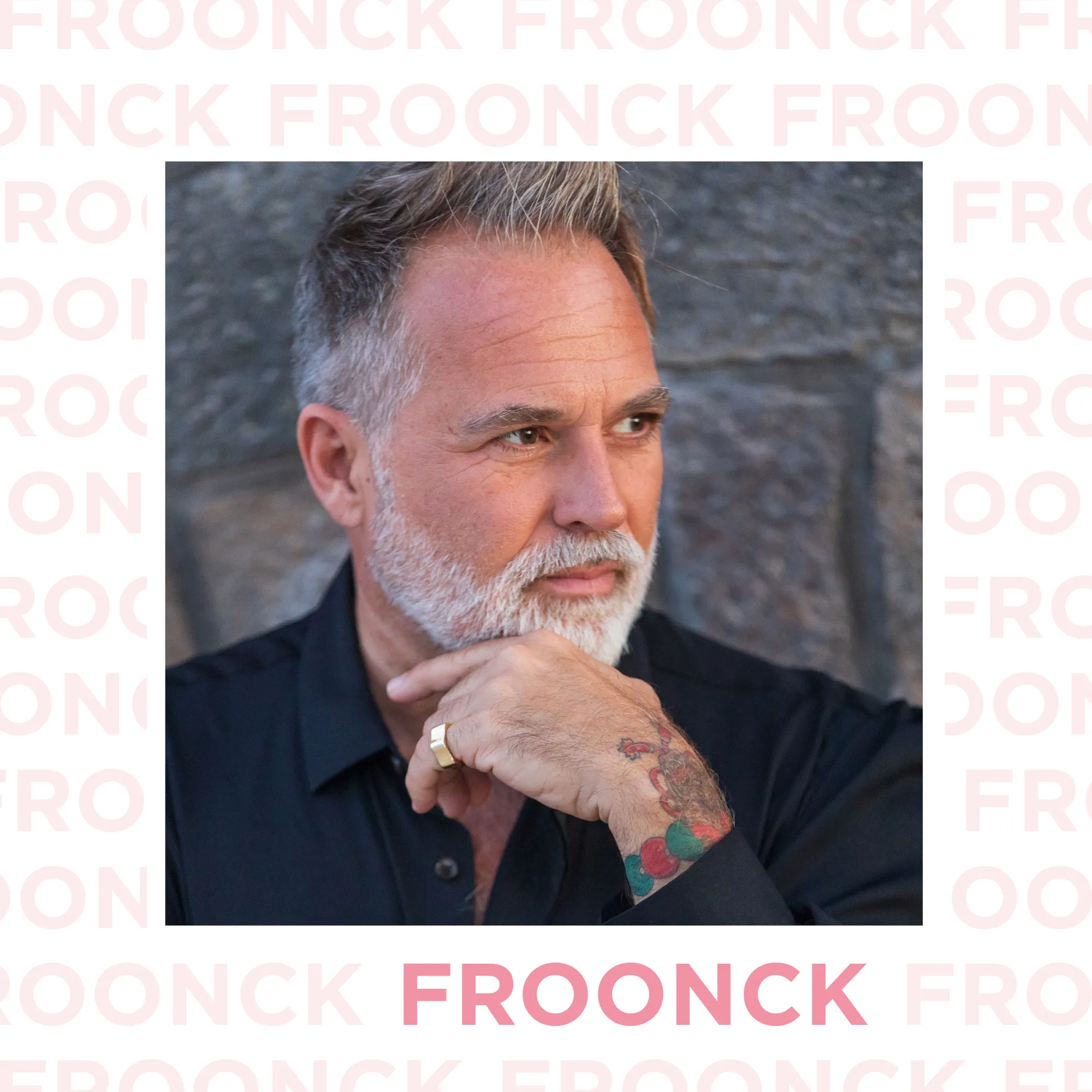 Quadratisches Porträt von Froonck in schwarzem Hemd, nachdenklich zur Seite schauend, mit der Hand am Kinn vor einer Steinmauer.