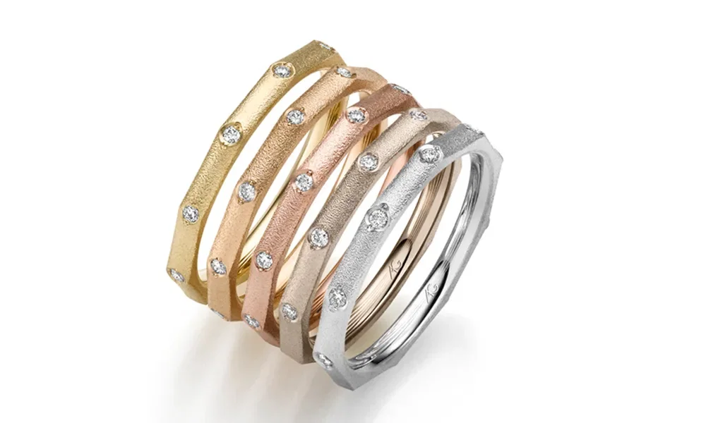 Eine elegante Kombination aus fünf schmalen Ringen in Gelb-, Rosé- und Weißgold. Die Ringe haben eine strukturierte, matte Oberfläche und sind mit kleinen Diamanten verziert, die rundherum angeordnet sind. Ihr kantiges Design verleiht den Ringen eine moderne Note.