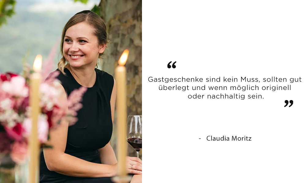 Claudia Moritz bei einer stilvollen Feier im Freien, von Kerzen und Blumendeko umgeben. In ihrem Zitat erklärt sie, dass Gastgeschenke kein Muss sind, aber idealerweise kreativ oder umweltfreundlich.