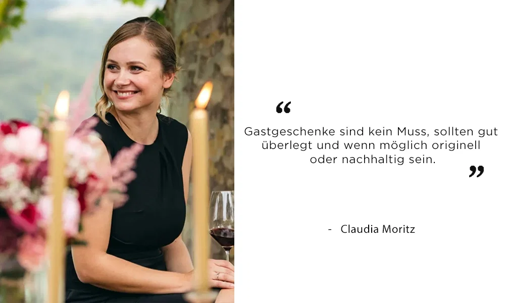 Claudia Moritz bei einer stilvollen Feier im Freien, von Kerzen und Blumendeko umgeben. In ihrem Zitat erklärt sie, dass Gastgeschenke kein Muss sind, aber idealerweise kreativ oder umweltfreundlich.