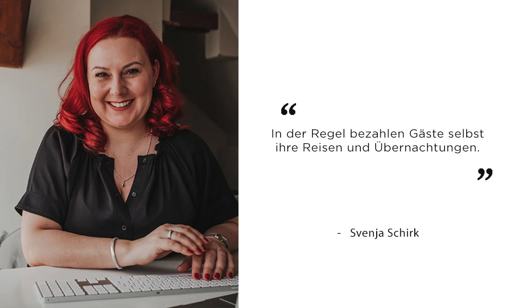 Svenja Schirk, freundlich lächelnd mit roten Haaren und schwarzem Outfit, sitzt am Schreibtisch. Ihr Zitat thematisiert die Kostenübernahme von Reise und Unterkunft durch Hochzeitsgäste.