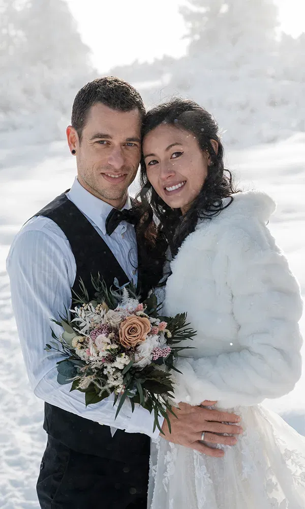 Hochzeitspaar beim Fotoshooting in einem schneebedeckten Wald