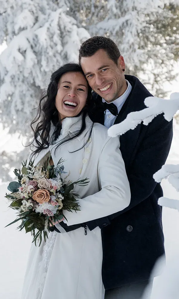 Hochzeitspaar beim Fotoshooting in einem schneebedeckten Wald
