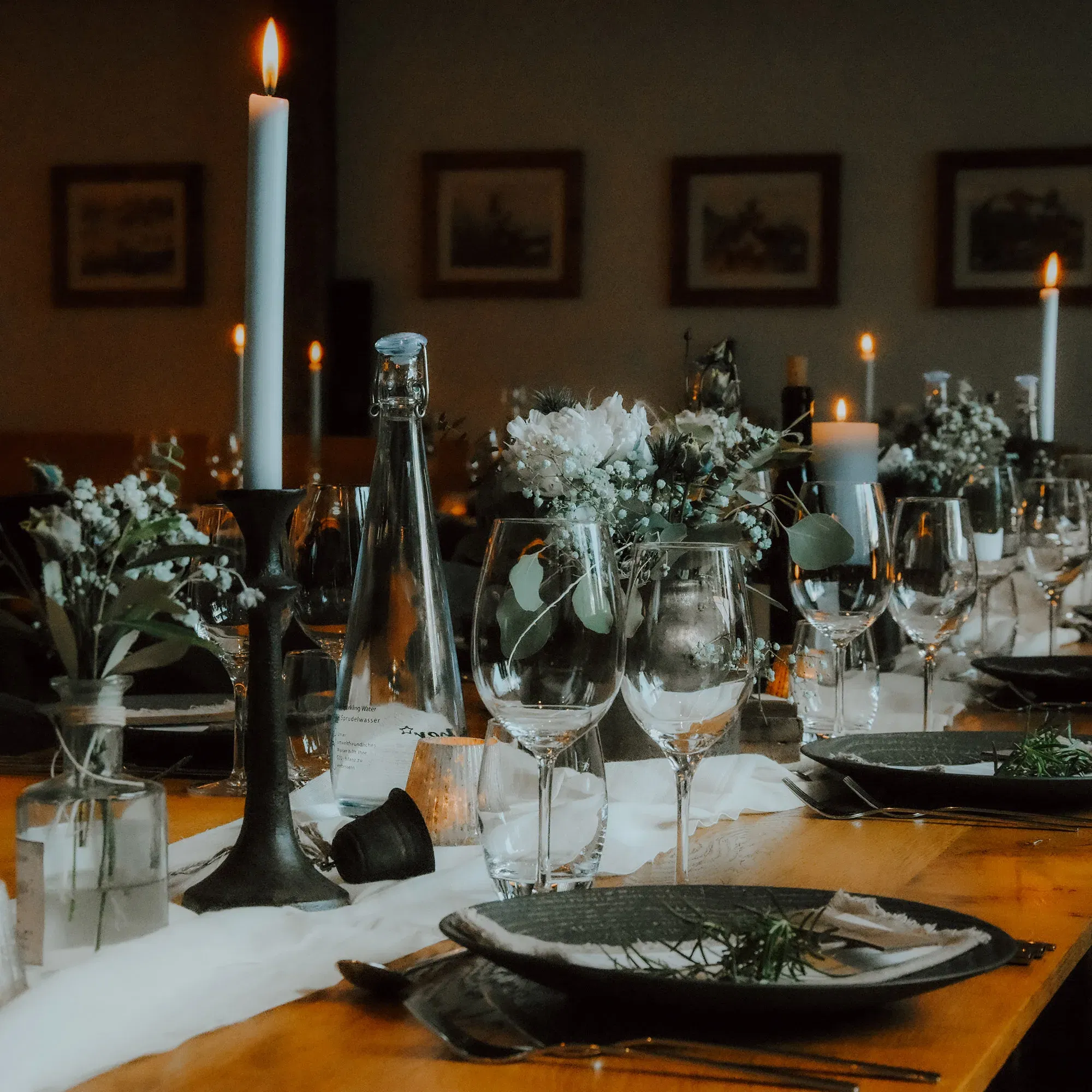 Ein schön gedeckter Tisch mit Kerzen, Blumen und Gläsern für eine Hochzeit. Die warme Beleuchtung durch Kerzen sorgt für eine romantische Atmosphäre.